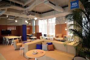 Collaborative workspace with a curved sofa, round tables, and a long table for meetings and work sessions.