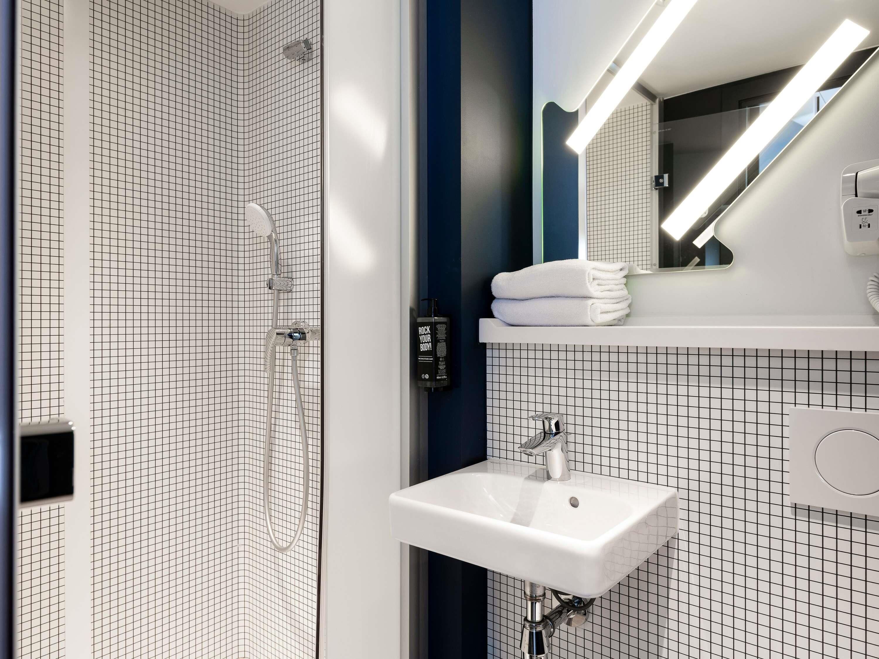 Un baño moderno con ducha, lavabo y espejo.
