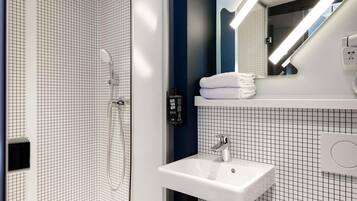 Un baño moderno con ducha, lavabo y espejo.