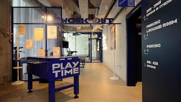 Un espace de travail moderne doté d’un espace « SÉANCE DE SPORT », d’une table « ESPACE DÉTENTE » et de panneaux indicateurs pour la « SALLE DE DÉPOSAGE DES BAGAGES » et les « CHAMBRES ».