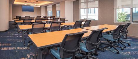 Une salle de conférence dotée de plusieurs tables et chaises, de grandes fenêtres et d’un plafond au design moderne.