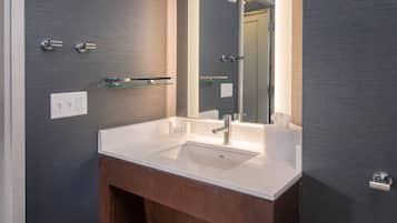 Un baño moderno con un lavabo blanco, un espejo y un mueble de tocador de madera.