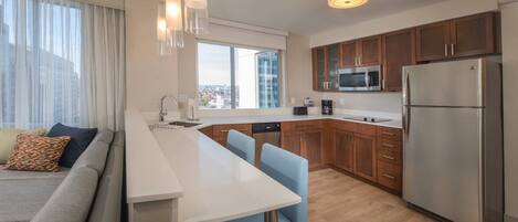 A modern kitchen with a central island, wooden cabinets, stainless steel appliances, and a city view through large windows.