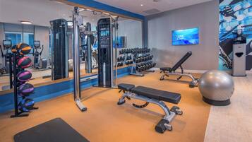 Une salle de sport équipée de matériel d’exercice, d’un banc, d’haltères et d’un grand miroir.