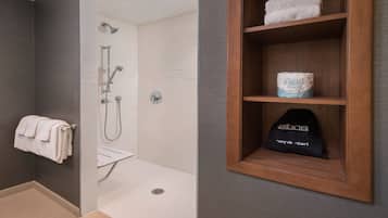A modern bathroom with a shower, a towel rack, and a shelf with toiletries.