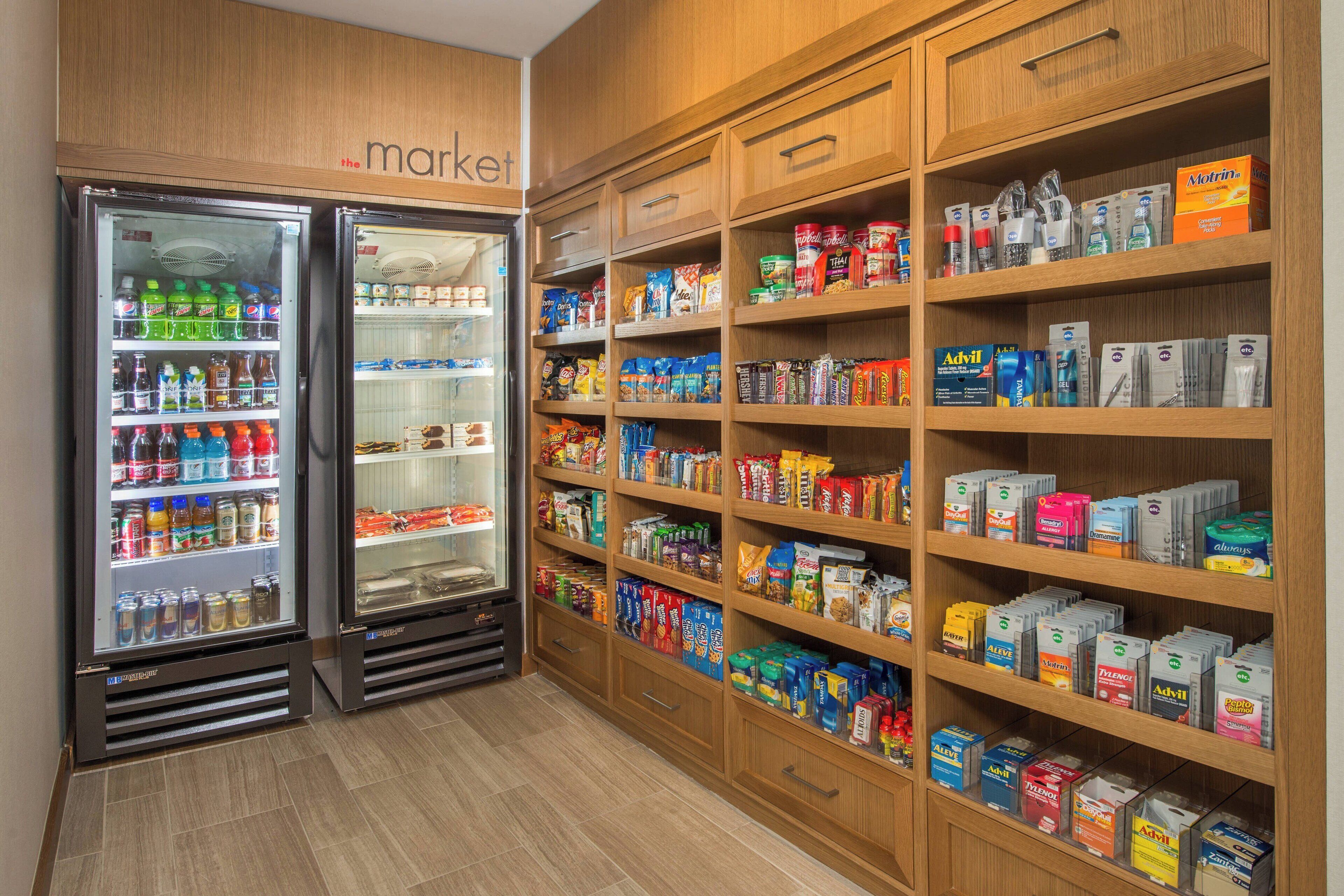 Una tienda de comestibles con refrigeradores para bebidas y estantes llenos de diversos productos alimenticios.
