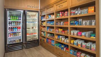 Una tienda de comestibles con refrigeradores para bebidas y estantes llenos de diversos productos alimenticios.