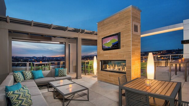 Una terraza en la azotea con chimenea integrada, asientos al aire libre y una pantalla de televisión.