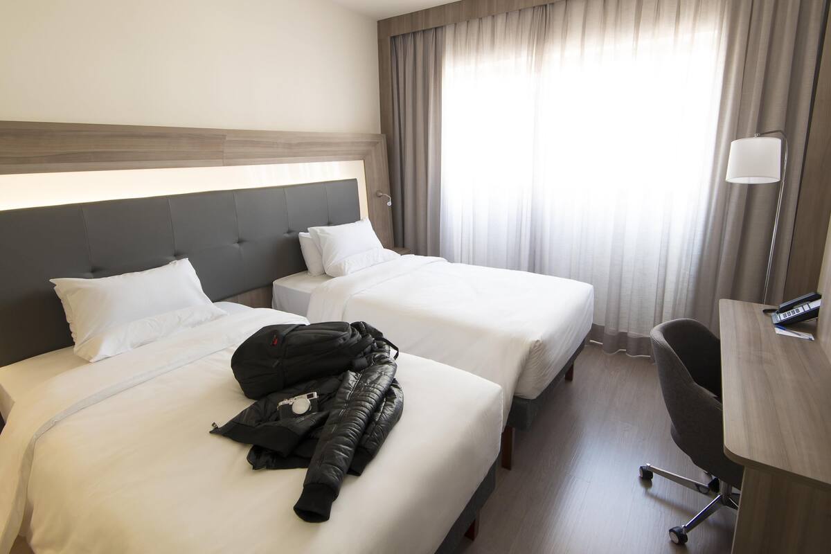Camera d'albergo con due letti, una scrivania e una sedia.