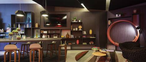 Une cuisine moderne dotée d’un bar, de tabourets en bois et d’un espace salon circulaire agrémenté d’un tapis.