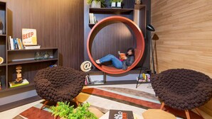 A modern interior with a circular seating area, a bookshelf, and a decorative sign. - Novotel São Paulo Berrini (São Paulo)