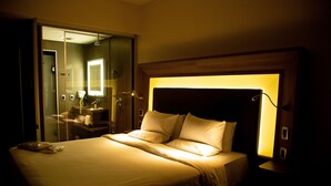 A hotel room with a large bed, a bedside table, a mirror, and a shower area visible through a glass door. - Novotel São Paulo Berrini (São Paulo)