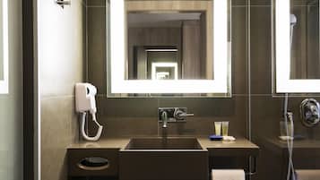 A modern bathroom with a large mirror, a sink, a hairdryer, and a shower.
