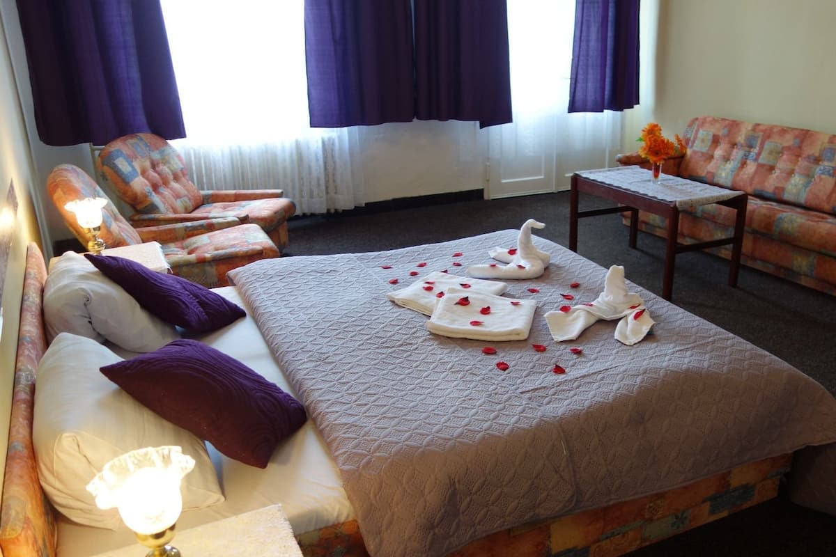 Quarto de hotel com uma cama, duas poltronas, um sofá e uma mesinha.