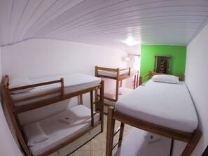 A dormitory room with bunk beds, a green wall, and a window with a curtain. - Beira Mar Hostel (Angra dos Reis)