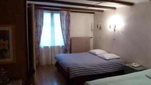 A bedroom with a bed, bedside table, and a window with curtains. - Hotel aux deux clefs (Marmoutier)