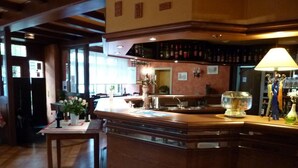 A bar area with a wooden counter, a lamp, and a decorative statue. - Hotel aux deux clefs (Marmoutier)