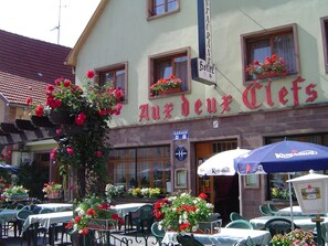 Un hotel llamado "Auerdeux Clevs" con mesas al aire libre y arreglos florales.