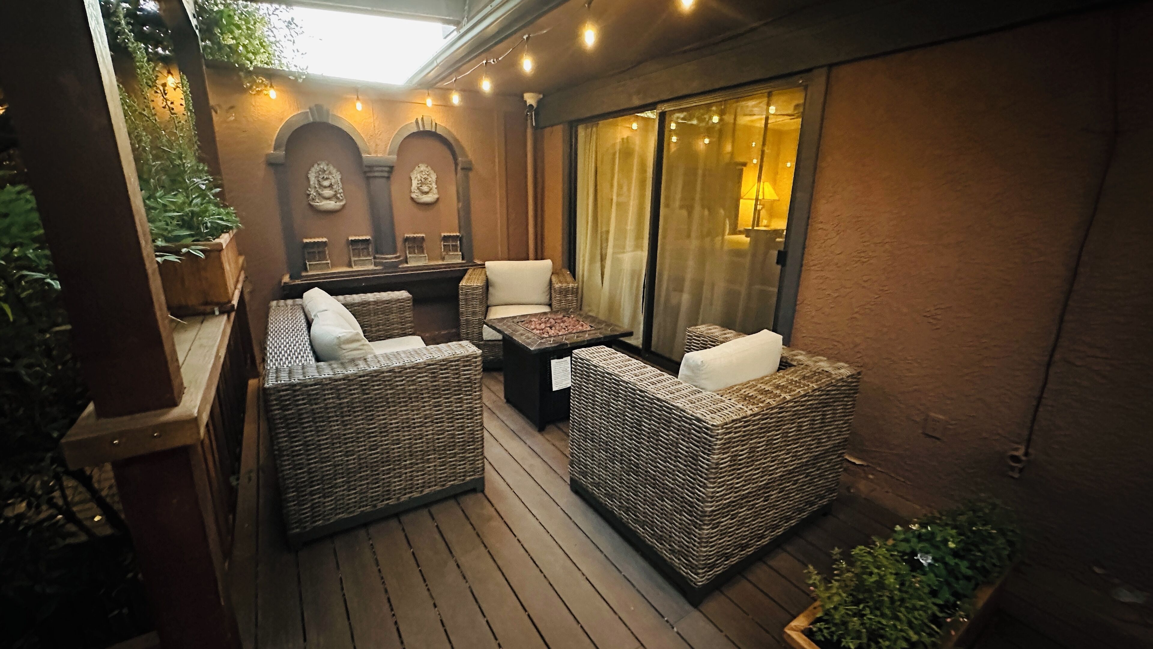 Un patio al aire libre con mobiliario de mimbre, una mesa y un banco acolchado.