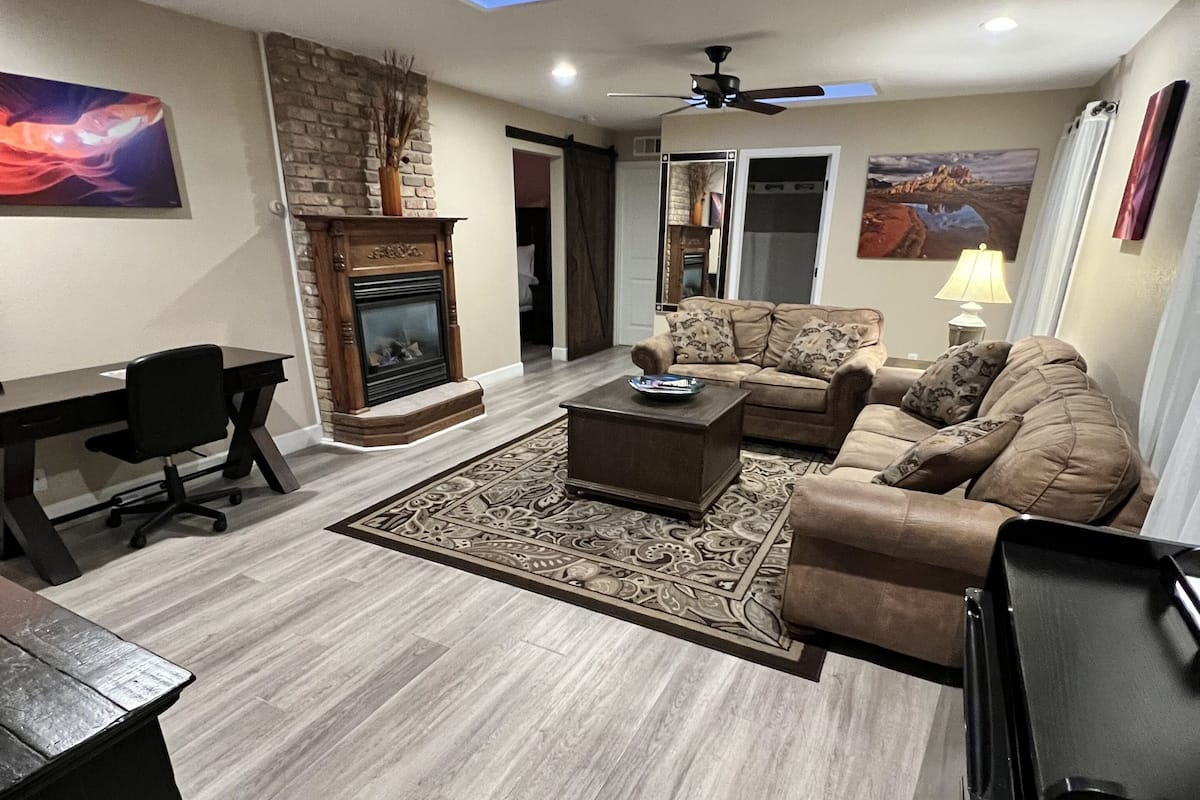 A living room with a fireplace, a ceiling fan, and a skylight.