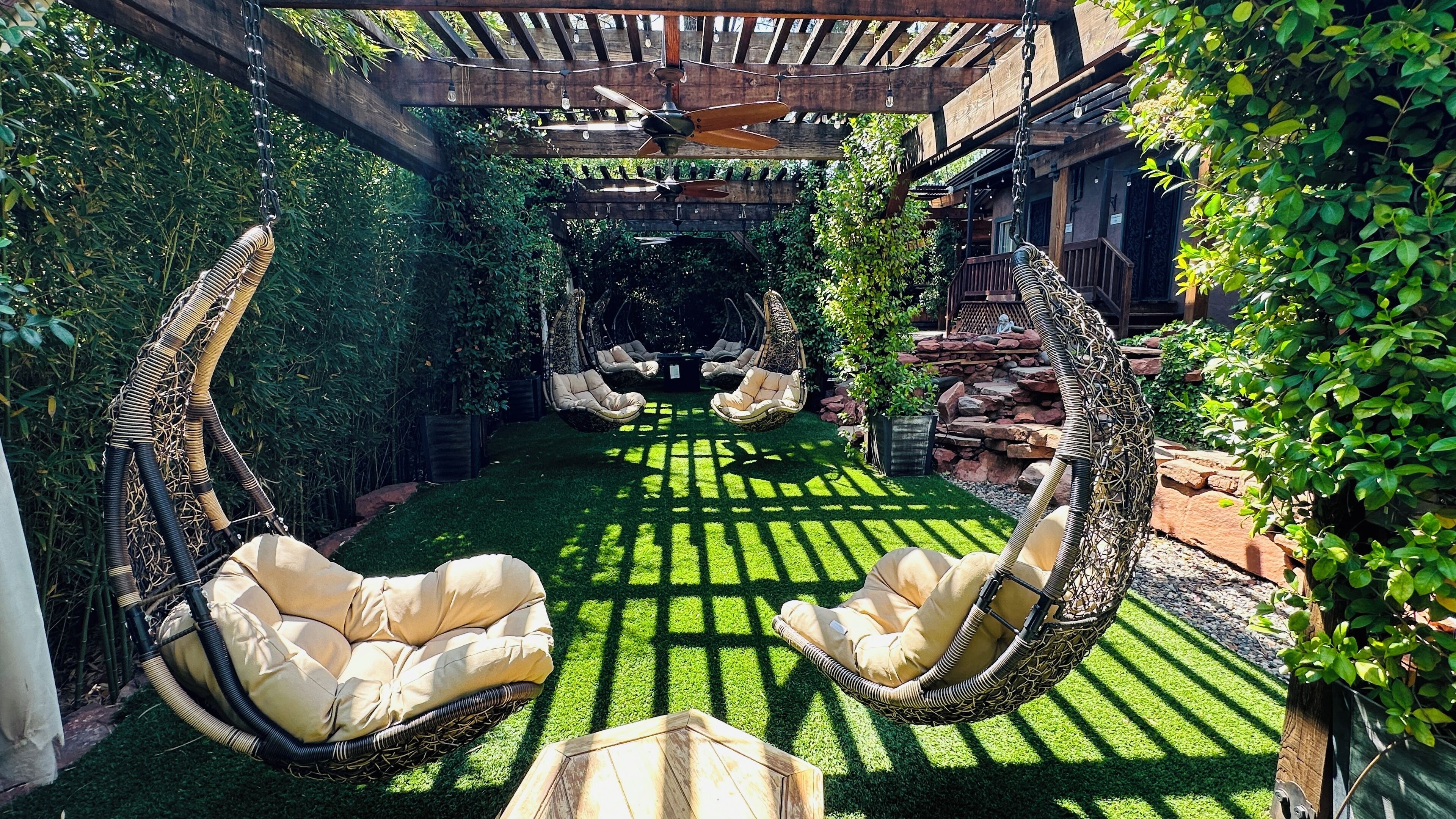 Un jardín con sillones colgantes y una pérgola.