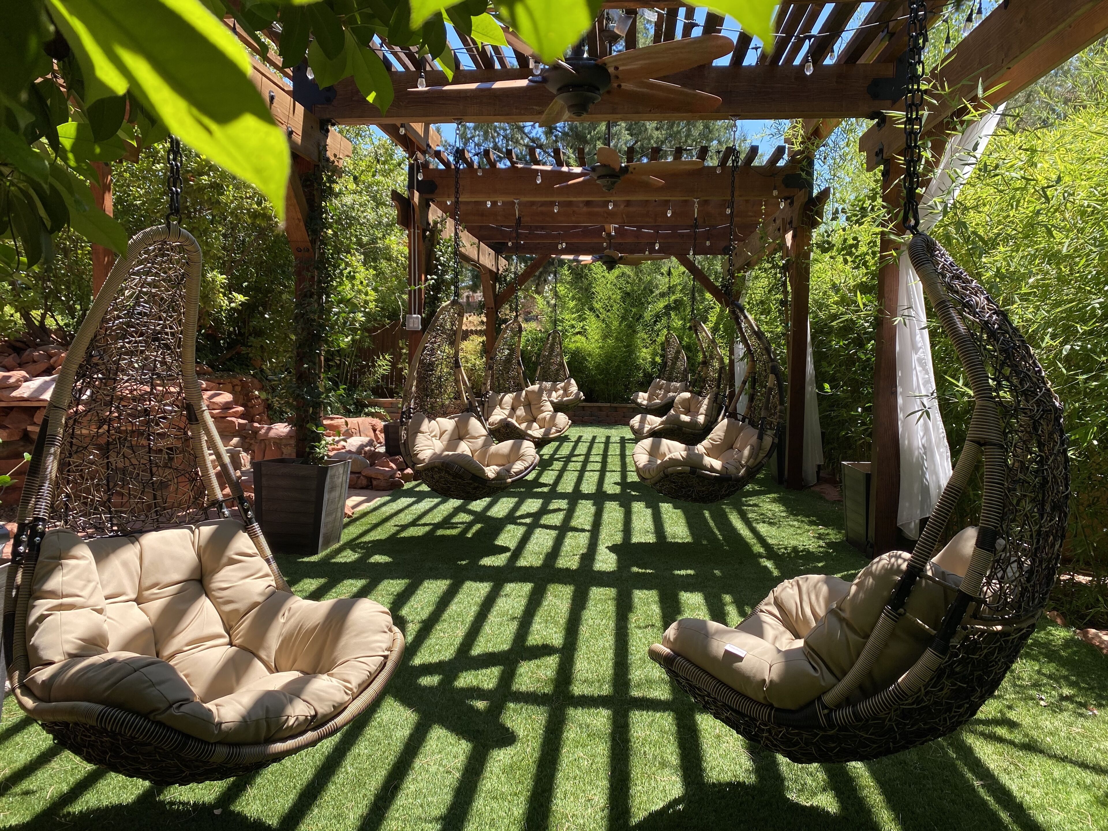 A garden with hanging chairs and a pergola.
