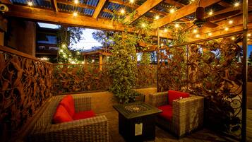 Un espace extérieur aménagé en terrasse, avec des meubles en osier, une petite table et des guirlandes lumineuses.