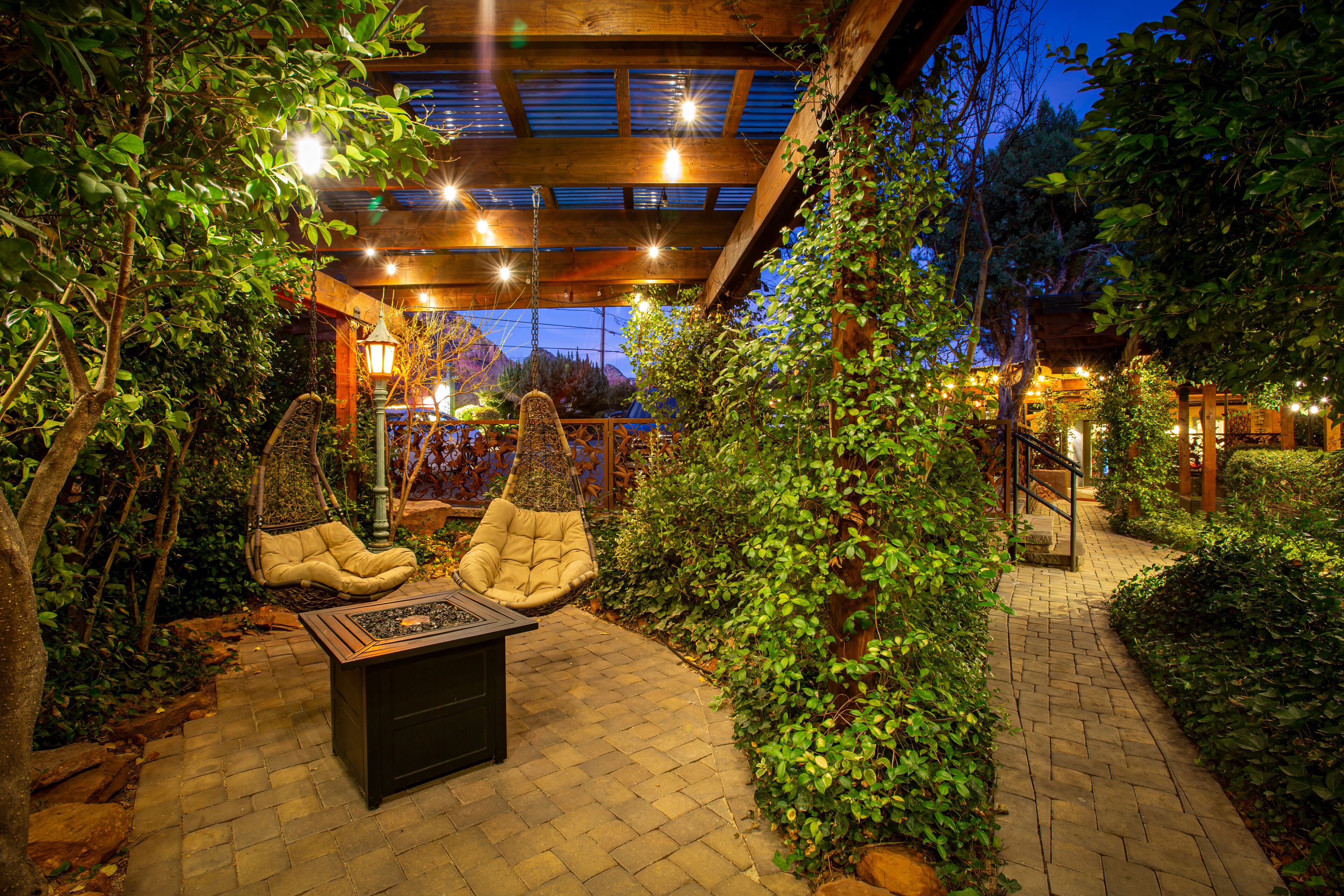 Un espacio de patio al aire libre con dos sillones acolchados, una mesita y un farol colgante.