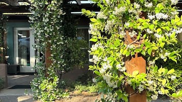 Un pasillo cubierto con una estructura de pérgola de madera, rodeado de exuberante follaje y plantas florecientes.