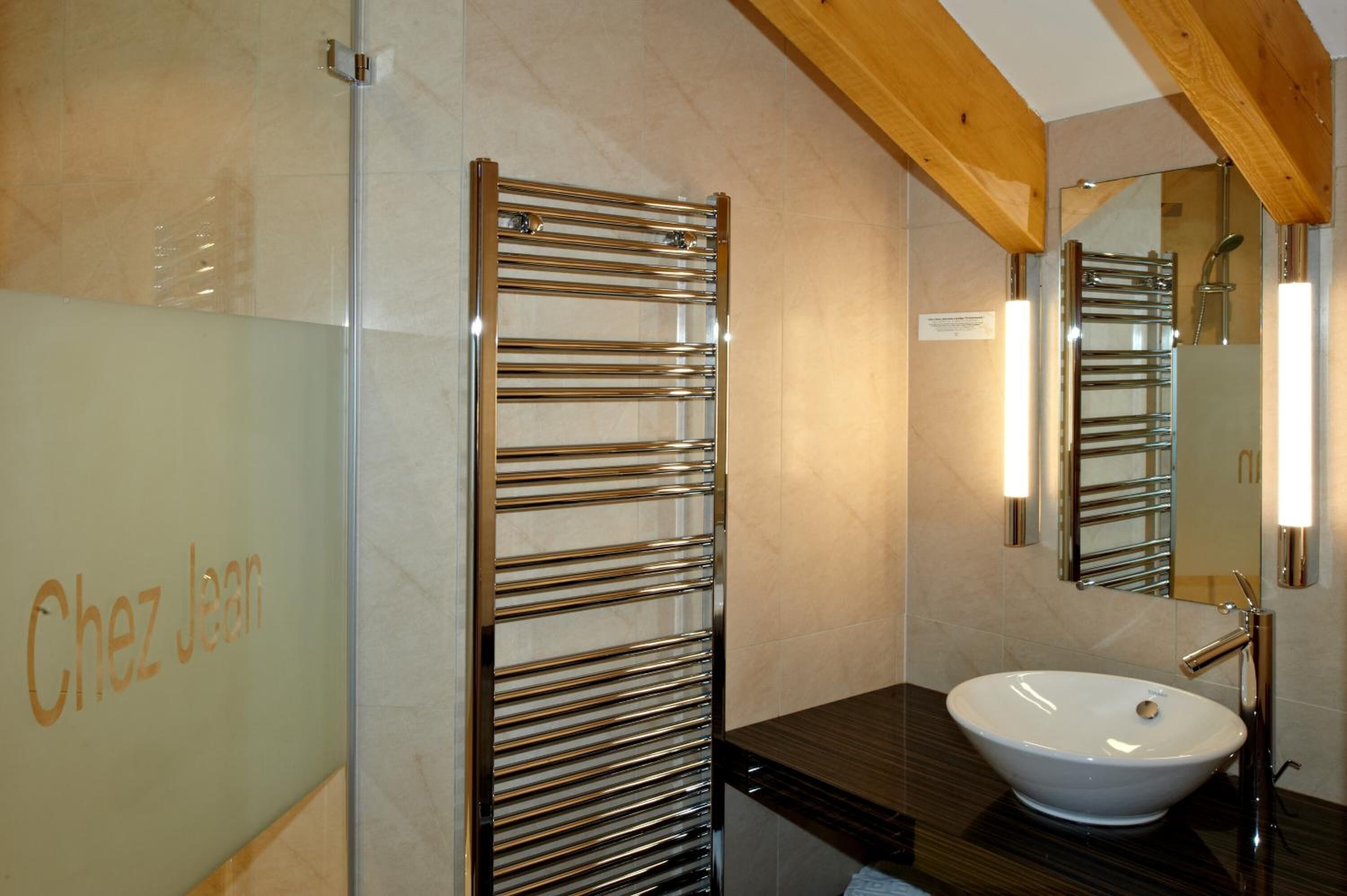 A bathroom with a glass shower enclosure, a towel rack, a sink, and a mirror.