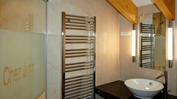 Une salle de bain avec une douche à parois de verre, un porte-serviettes, un lavabo et un miroir.