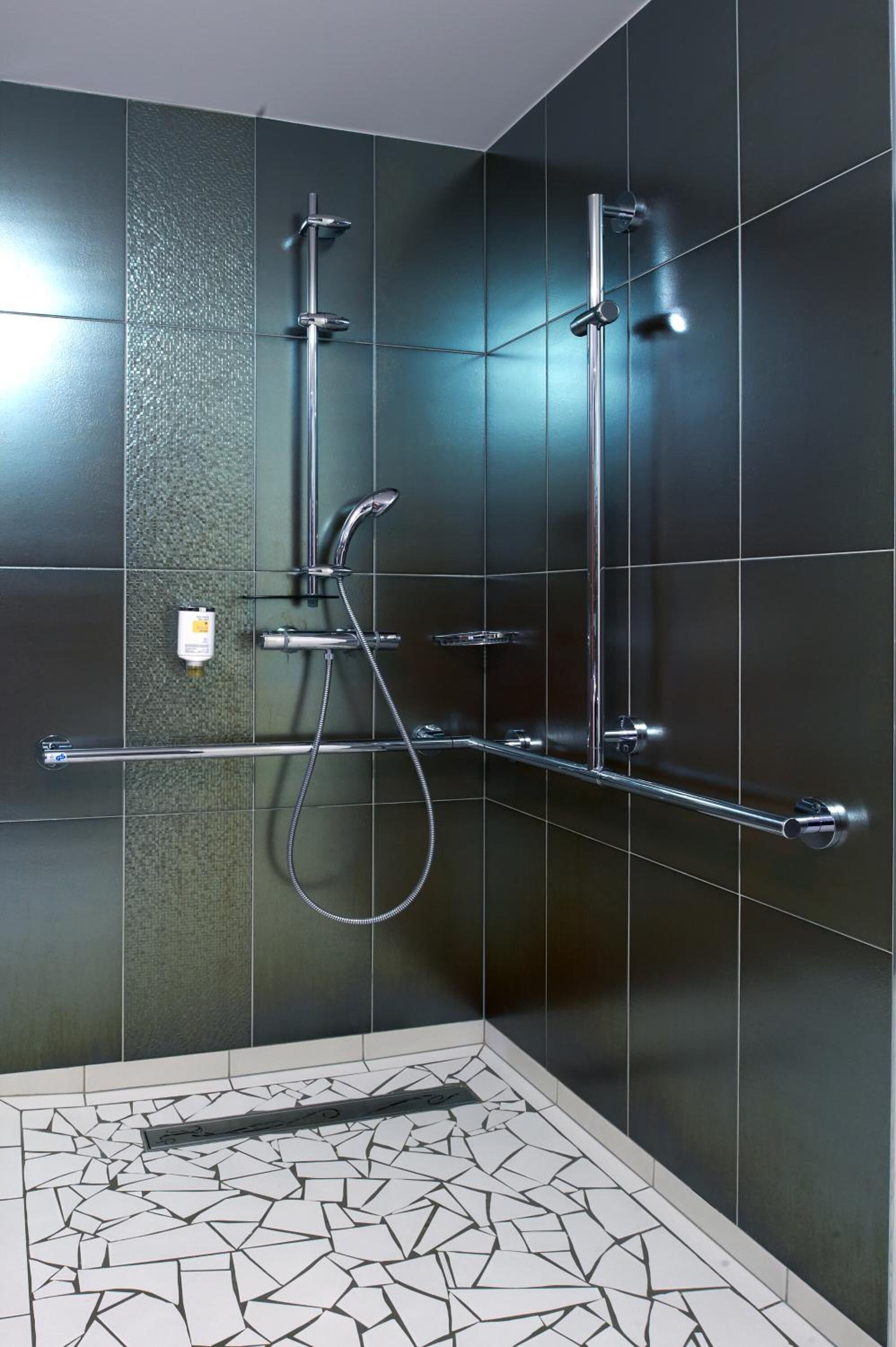 Una ducha moderna con detalles cromados y piso de mosaico.