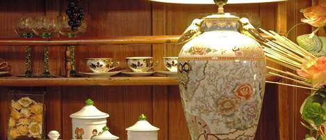 Una exhibición de menaje de cocina de cerámica que incluye un jarrón grande, teteras y tazas con diseños florales.