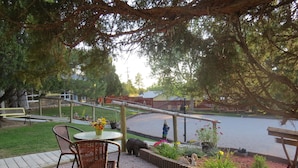 Un espace patio aménagé avec une table et des chaises, entouré d’un jardin agrémenté de plantes et d’une statue de cygne décorative.