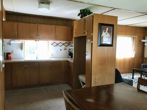 A compact kitchen with wooden cabinets, a countertop, and a dining area with a table and chairs.