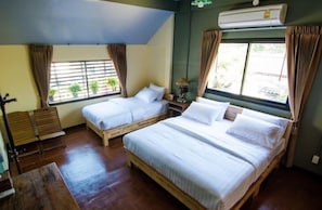 A room with two wooden beds, a bench, a table, and a window with curtains.