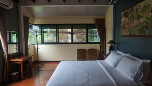 A bedroom with a large bed, wooden headboards, a desk, and a standing lamp.