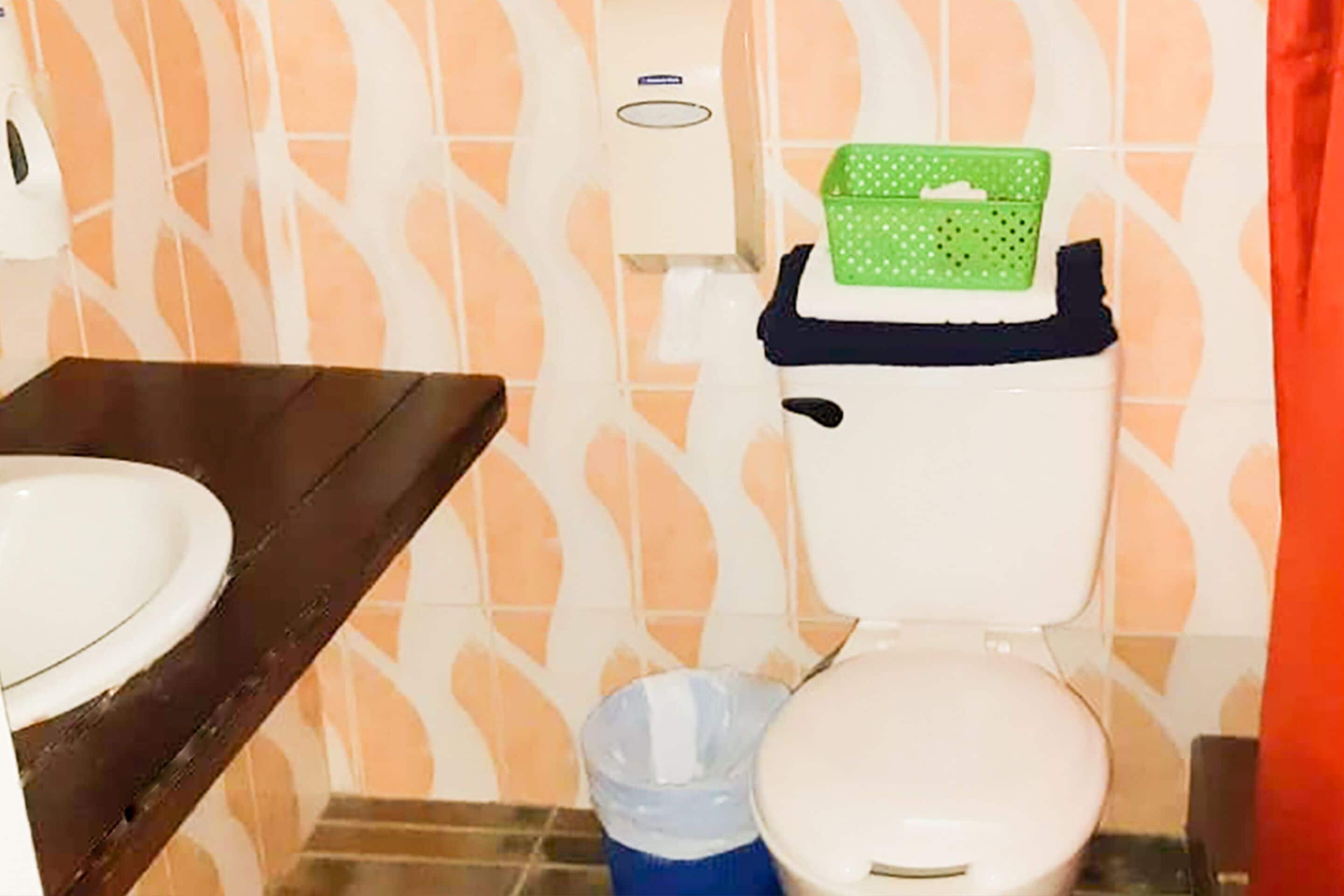 A bathroom with a toilet, a sink, and a trash bin.