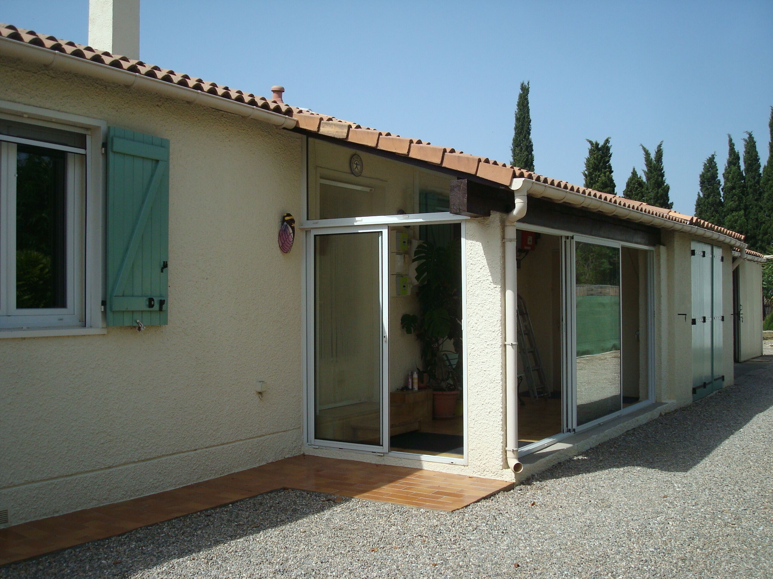 A house with a tiled roof, a sliding glass door, and a small porch area.