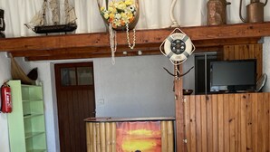 Un comedor con una mesa preparada para cuatro personas, un televisor y un modelo decorativo de barco.