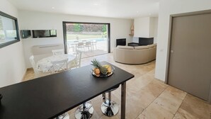 A modern kitchen with a dining area, a pool view, and a living area with a sofa.