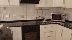 Eine Küche mit weißen Schränken, einer schwarzen Arbeitsplatte, einem eingebauten Ofen, einer Mikrowelle und hängenden Küchenutensilien.