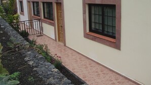 Ein Gebäude mit befestigtem Pflasterweg, einer Holztür und einem Fenster mit Steinrahmung.