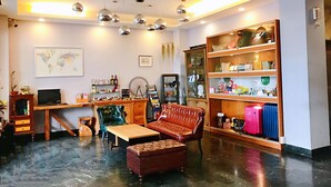 A modern living room with a wooden coffee table, leather sofa, and a bookshelf filled with various items. - Prince To Travel Hotel (Chiayi City)