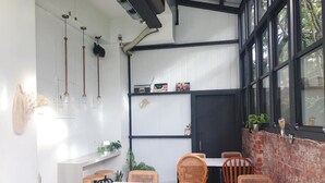 A dining area with wicker chairs, white tables, and a brick wall. - Prince To Travel Hotel (Chiayi City)