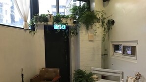 A cozy corner with a brown leather chair, a small round table, a white bench, and various potted plants. - Prince To Travel Hotel (Chiayi City)