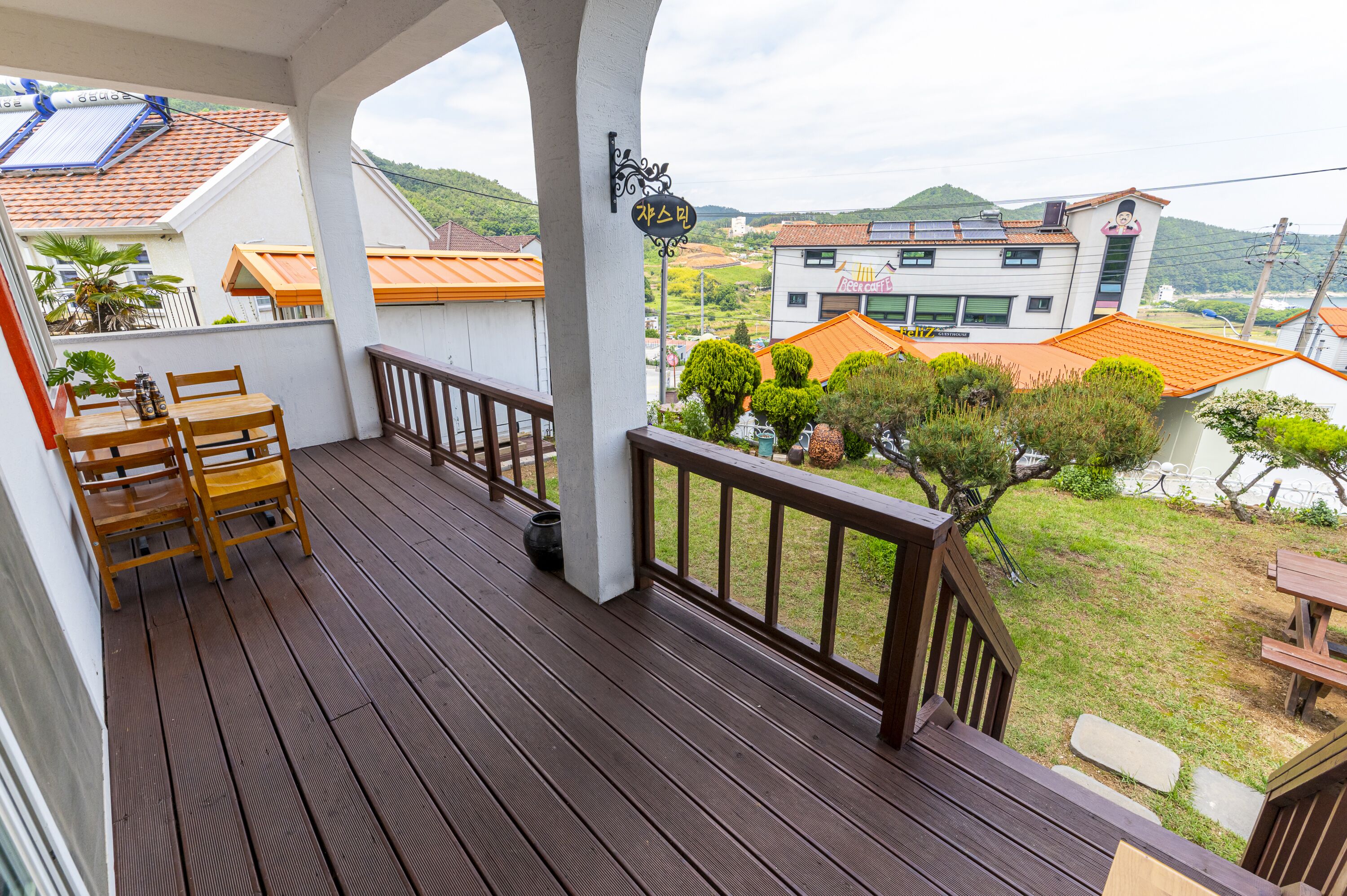 A wooden deck with a railing, a table with chairs, and a sign indicating a restaurant.