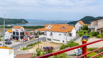 Une ville côtière avec une pizzeria, un bâtiment blanc doté d’un toit rouge et offrant une vue sur la mer et les collines.