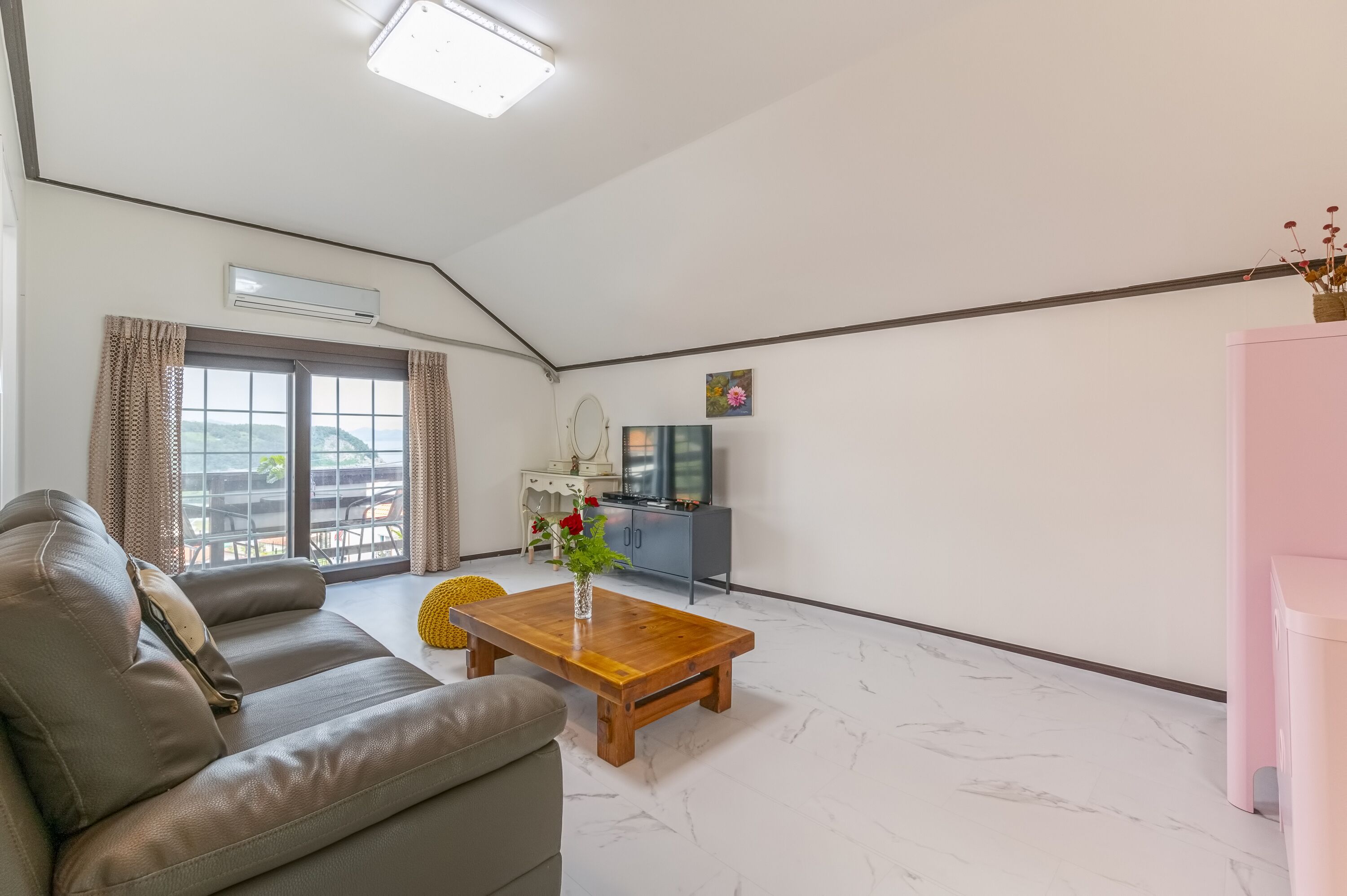 A modern living room with a sofa, a wooden coffee table, and a TV.