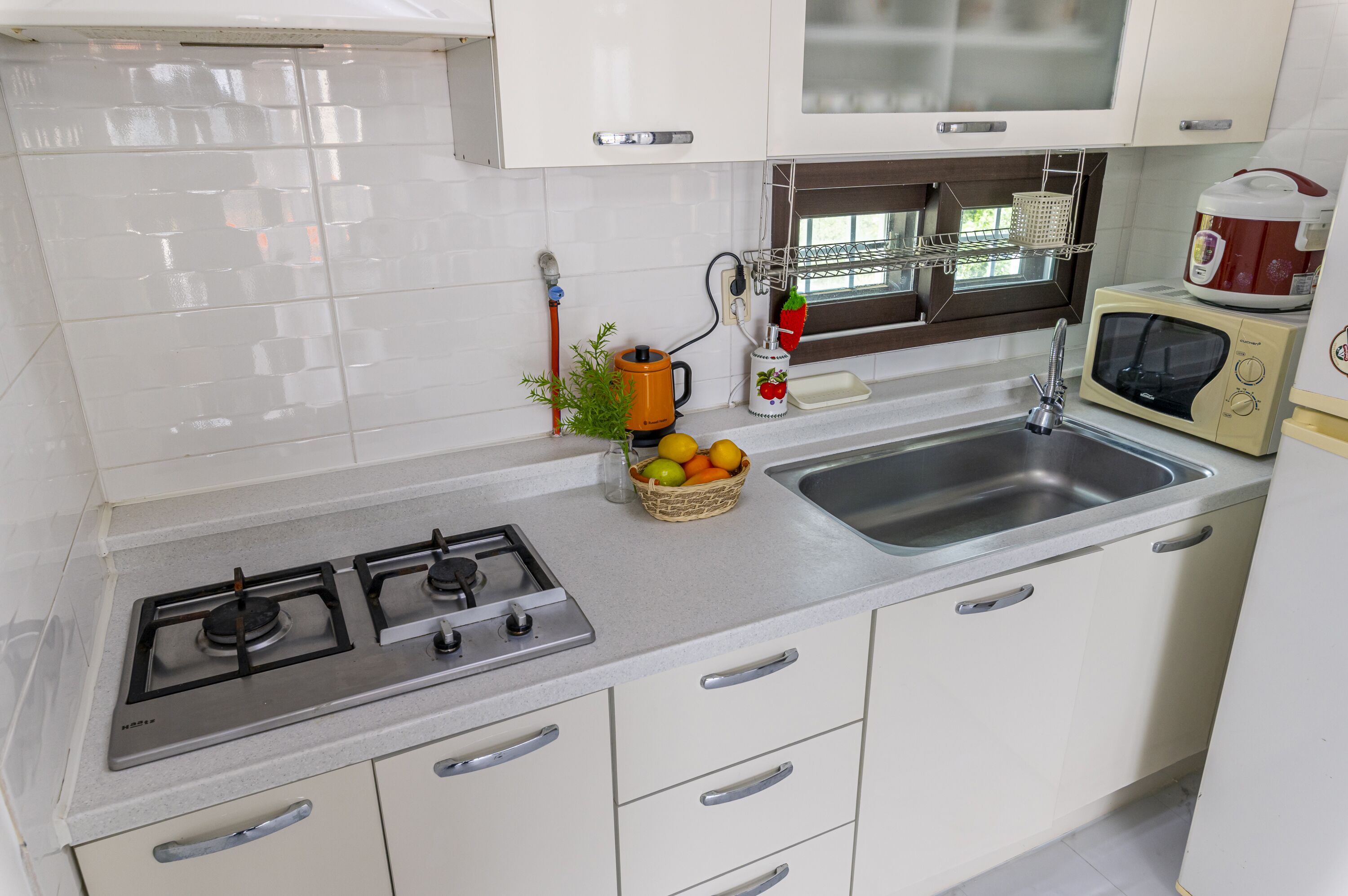 A kitchen with white cabinets, a gas stove, a microwave, and a sink.